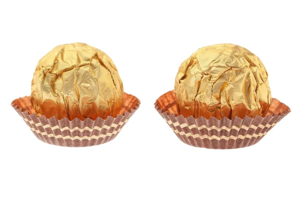 Dwa cukierki czekoladowe, owinięte w złoto. na białym tle. — Zdjęcie stockowe