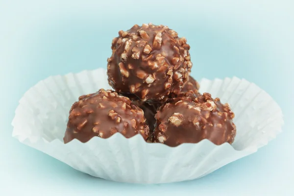 Caramelos de chocolate del grupo en una cesta de papel blanco. en un backg azul —  Fotos de Stock