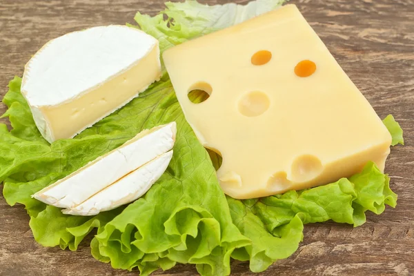 Uno spuntino su un tavolo in legno da due tipi di formaggio su un pezzo di l — Foto Stock