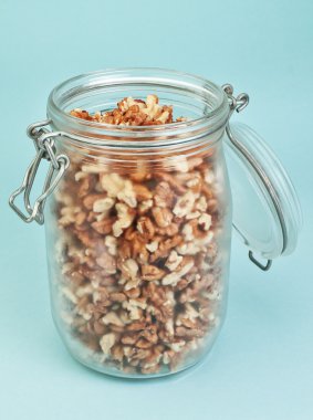 Cam Kavanoz ceviz ile. üzerinde mavi bir arka plan.