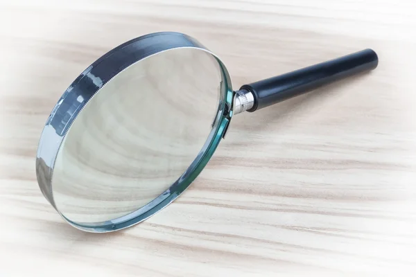 Magnifying glass magnifying glass on a wooden texture. — Stock Photo, Image