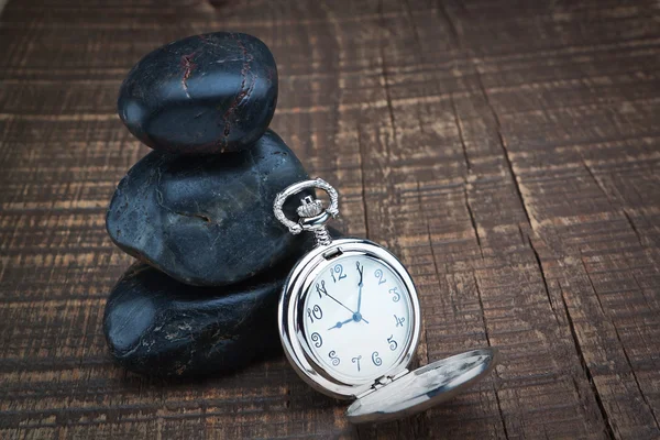 Zegarek kieszonkowy w pobliżu kamienie spa. na drewniane tekstury. — Zdjęcie stockowe