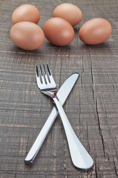 Huevos cubiertos de tenedor y cuchillo y Pascua. en una textura de madera. —  Fotos de Stock