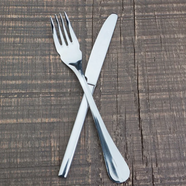 Instrumento de mesa plata de un tenedor y un cuchillo en una textura de madera. — Foto de Stock