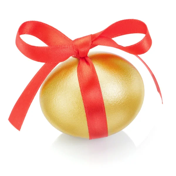 Złote jajo wielkanocne z czerwoną kokardą. na białym tle. — Zdjęcie stockowe