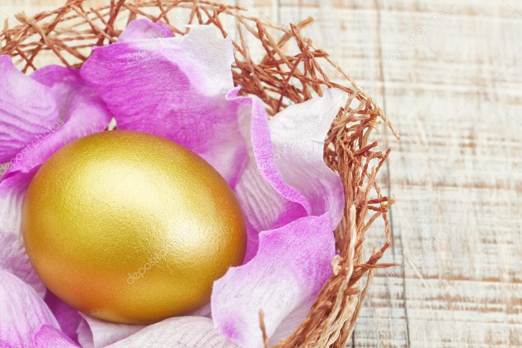 Golden egg in a nest with purple petals.