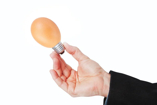 Mano tiene un uovo con un pezzo della lampada elettrica. su un retro bianco — Foto Stock