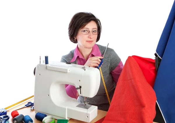 Middle-aged woman holding a pair of scissors at the sewing machi — Stock Photo, Image