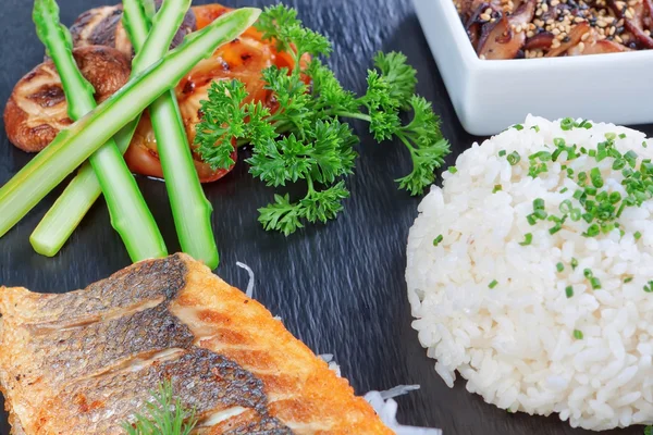 A delicious piece of fish on a background of greens, rice and mu — Stock Photo, Image