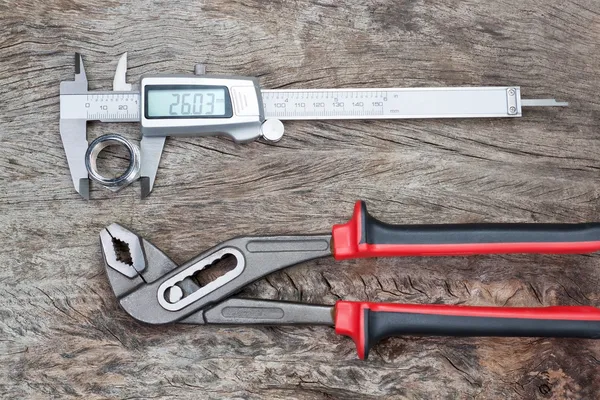 Compasso de calibre e chave ajustável com um detalhe em uma textura de madeira. — Fotografia de Stock