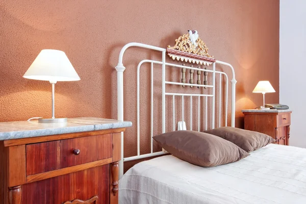 Lampshades near the old classic bed in the bedroom. Brown color. Stock Image