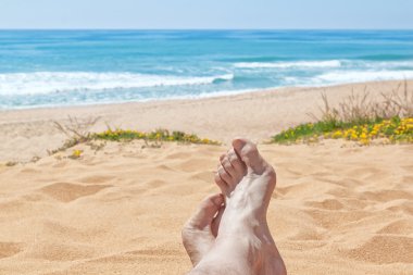 tatile denize karşı sahilde çıplak bacaklar.