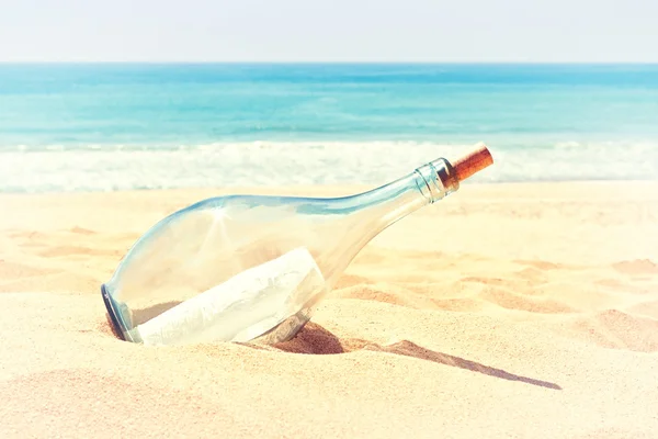 Una botella con una carta de socorro en la arena de la playa. en —  Fotos de Stock