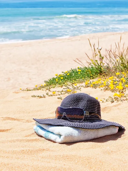 Kvinnors Panama hatt med solglasögon på en handduk på stranden i th — Stockfoto