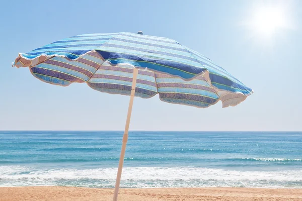 Niebieski parasol na plaży, w pobliżu morza. — Zdjęcie stockowe