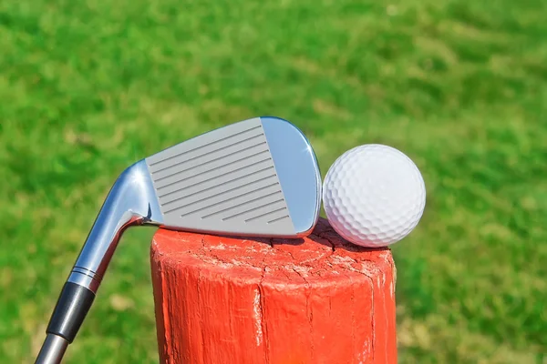 Palo de golf boca abajo sobre un pedestal de bola de madera en el césped. c —  Fotos de Stock