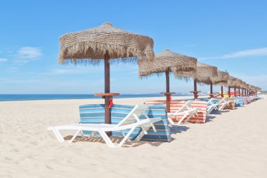 ahşap plaj şemsiyeleri ve sahilde şezlong. tatil için