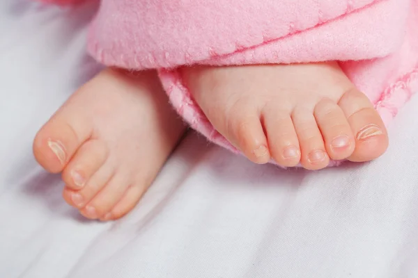 Niedlichen Finger auf die Beine des Säuglings. in einer rosa Decke. — Stockfoto