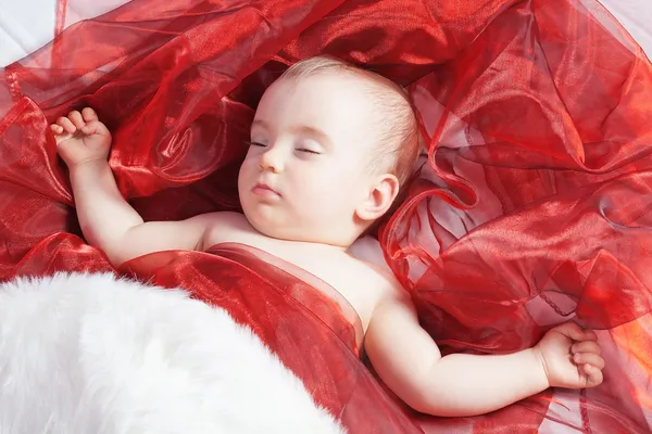 Bellissima bambina dorme su un rosso. Close-up. — Foto Stock