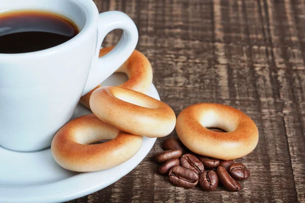 A cup of coffee with baked bagels, close-up. Coffee beans on the — Stock Photo, Image