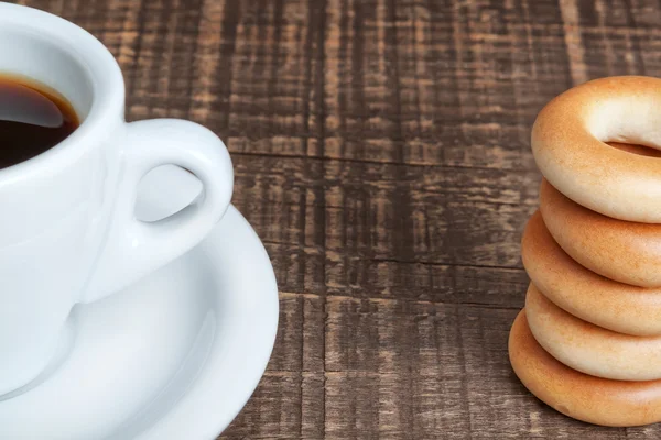 Uma xícara de café e pãezinhos cozidos close-up. em uma textura de madeira. — Fotografia de Stock