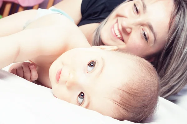 Glad, mor och barn leker på sängen. närbild. — Stockfoto