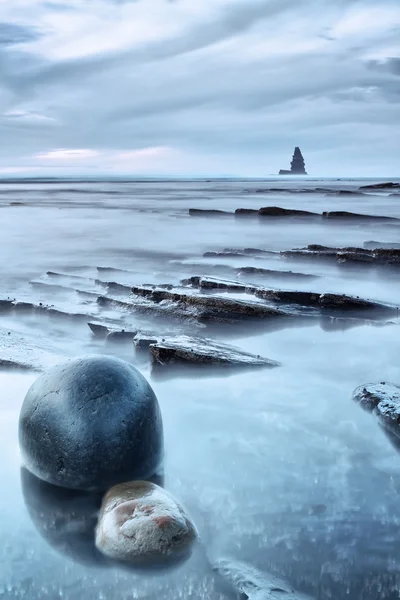 Seascape av klippor och hav vid solnedgången. en rund sten i händer — Stockfoto