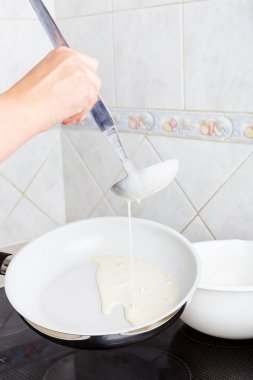 Kız bir tavada kızartma krep. mutfakta ev. yakın çekim.