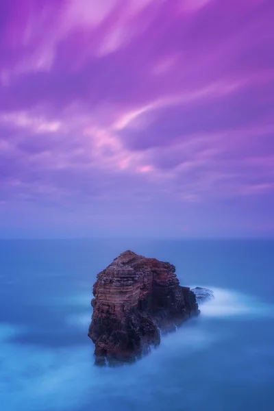 Montanha como uma fortaleza no mar no mar tempestuoso e céu rosa. Portugal. — Fotografia de Stock