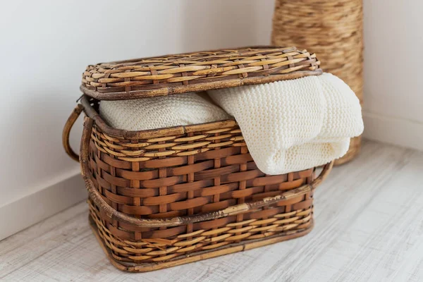 A wicker straw and bamboo chest of drawers, in the interior with bedspreads, blankets, a blanket and towels. For interior decoration. — Stock Photo, Image