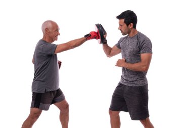 Yaşlı adam savunmada boks eldiveniyle vuruyor, kişisel fitness antrenörü, birlikte çalışma konsepti. Beyaz arkaplanda.