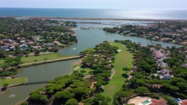 Vale de Lobo, Algarve, Portekiz, Avrupa 'daki Quinta do Lago tatil köylerinin hava manzarası. Yeşil manzaralı, arka planda dağlar olan lüks kulübelerin çatıları. Golf alanları.