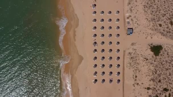 Vista aérea superior da estância balnear portuguesa. Parassóis e espreguiçadeiras estão localizados de cima para baixo na praia amarela. Algarve — Vídeo de Stock
