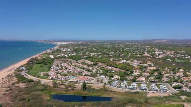 Flygöversikt över Quinta do Lago semesteranläggningar i Vale de Lobo, Algarve, Portugal, Europa. Skott av hustak av lyxstugor i grönt landskap med berg på bakgrunden. Golfplaner. — Stockvideo
