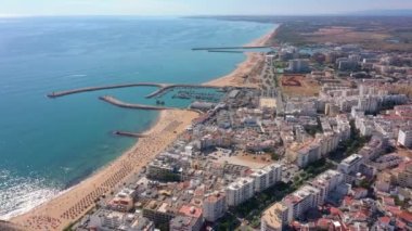 İnsansız hava aracı görüntüleri, Atlantik Okyanusu kıyısında turist kasabası Quareira 'yı çekiyor, turistlerle dolu plajlar. Portekiz, Algarve.