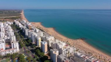 İnsansız hava aracı görüntüleri, Atlantik Okyanusu kıyısında turist kasabası Quareira 'yı çekiyor, turistlerle dolu plajlar. Portekiz, Algarve.