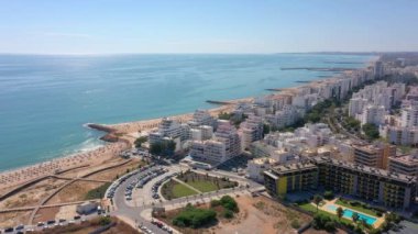 İnsansız hava aracı görüntüleri, Atlantik Okyanusu kıyısında turist kasabası Quareira 'yı çekiyor, turistlerle dolu plajlar. Portekiz, Algarve.