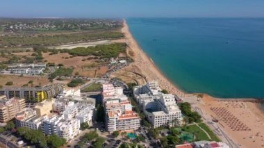 İnsansız hava aracı görüntüleri, Atlantik Okyanusu kıyısında turist kasabası Quareira 'yı çekiyor, turistlerle dolu plajlar. Portekiz, Algarve.