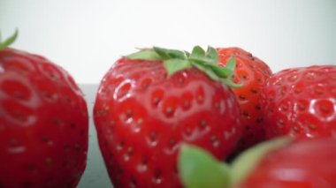 Olgun, taze, doğal çilekler yansımada, aşırı makroda, yakın çekim. İleri, geri hareket.