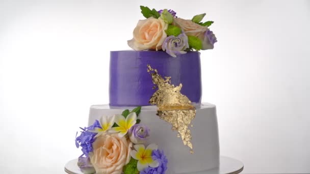 Heerlijke feestelijke slagroomtaart met paarse rozen. Ze draaien op de achtergrond. Voor de bruiloft. — Stockvideo