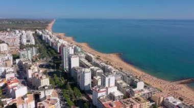 İnsansız hava aracı görüntüleri, Atlantik Okyanusu kıyısında turist kasabası Quareira 'yı çekiyor, turistlerle dolu plajlar. Portekiz, Algarve.