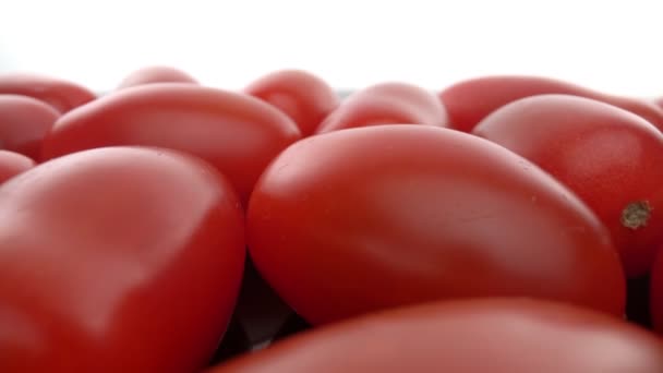 Reife rote biologische Tomaten in einer Reihe auf einer glatten Glasoberfläche. Vorwärts, rückwärts. Extremes Makro. — Stockvideo