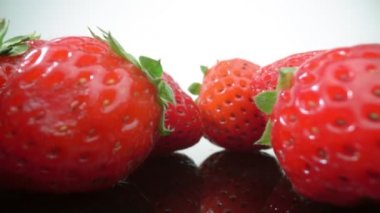 Olgun, taze, doğal çilekler yansımada, aşırı makroda, yakın çekim. İleri, geri hareket.