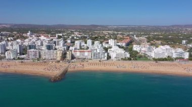 İnsansız hava aracı görüntüleri, Atlantik Okyanusu kıyısında turist kasabası Quareira 'yı çekiyor, turistlerle dolu plajlar. Portekiz, Algarve.