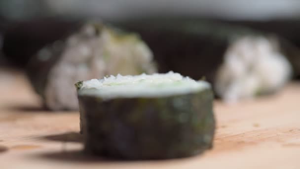 O chef estabelece, define para peças de entrega de sushi e rolo feito de frutos do mar com ingredientes asiáticos. Fecha, macro. O fundo está desfocado. Movimento lento — Vídeo de Stock