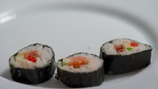 El chef se acuesta, establece para la entrega piezas de sushi y rollo de mariscos con ingredientes asiáticos. Primer plano, macro. El fondo está borroso. — Vídeo de stock