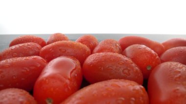 Pürüzsüz cam bir yüzey üzerinde olgun kırmızı biyolojik domatesler. İleri doğru, geriye doğru. Ekstrem makro.