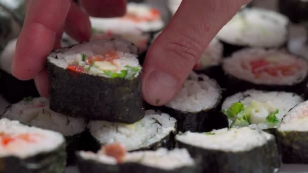 Kocken lägger ner, sätter för leverans bitar av sushi och rulle gjord av skaldjur med asiatiska ingredienser. Närbild, makro. Bakgrunden är suddig. Långsamma rörelser — Stockvideo
