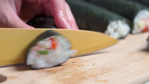 Шеф-повар режет суши и булочки из морепродуктов с азиатскими ингредиентами с ножом. Закрывай, макро. Фон размыт.. — стоковое видео