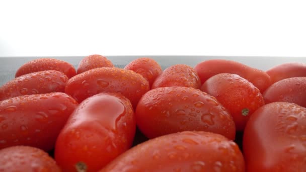 Pürüzsüz cam bir yüzey üzerinde olgun kırmızı biyolojik domatesler. İleri doğru, geriye doğru. Ekstrem makro. — Stok video